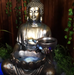 Tranquil sitting Buddha with bowl water feature fountain slight right angle view